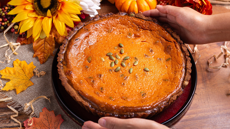 Pumpkin pie being placed on a table with fall decor