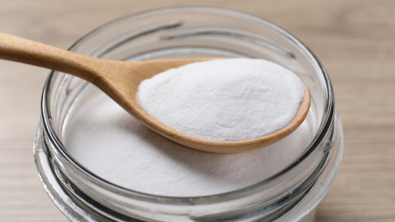 closeup of jar of baking soda with wooden spoon