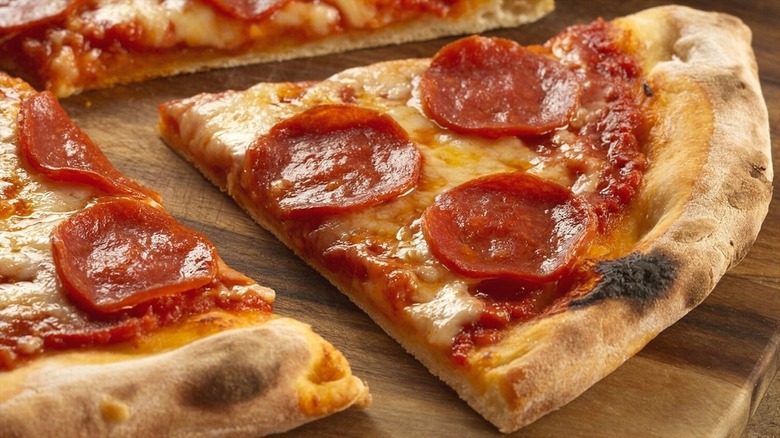 Slices of pepperoni and cheese pizza on a wooden serving board