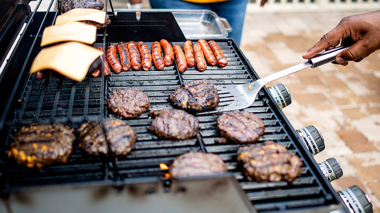 Person grilling outside holding spatula