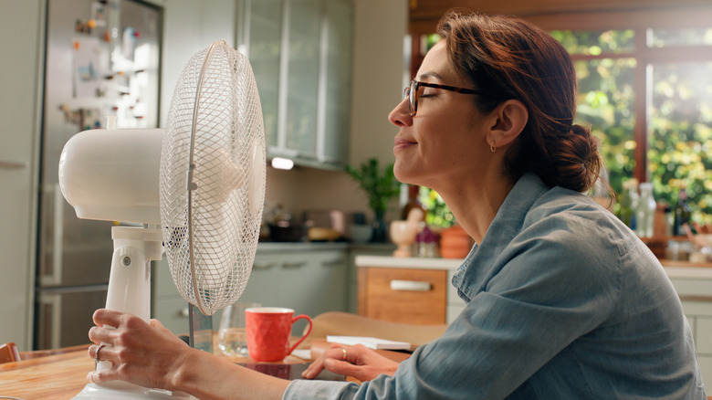 Woman sitting in front of a fan in the kitchen
