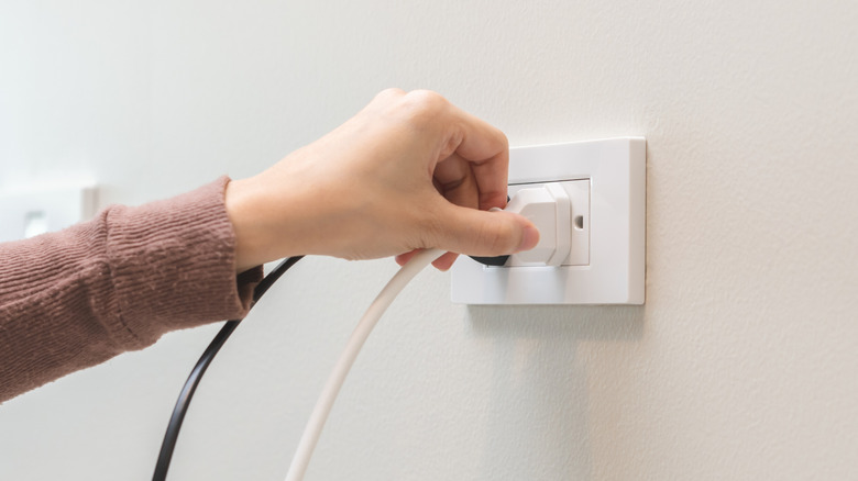 Hand unplugging outlet from a socket