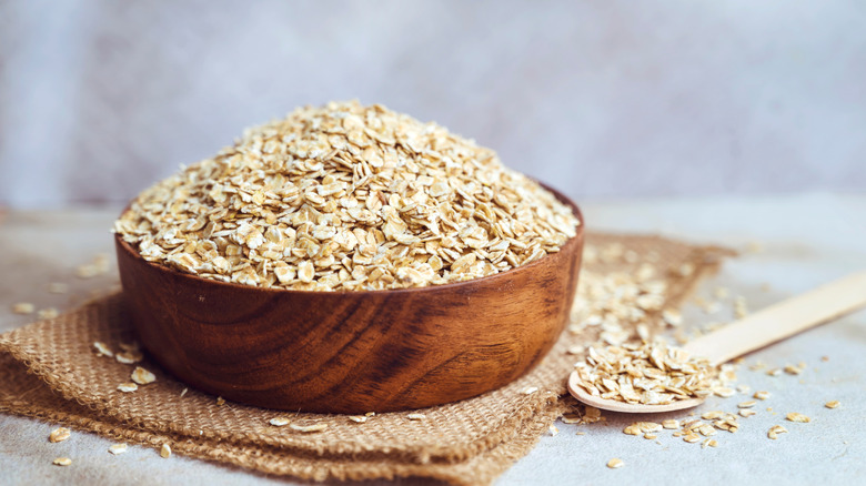 A wooden bowl filled to the brim with raw oats
