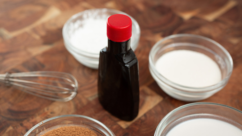 A bottle of vanilla extract surrounded by other baking ingredients