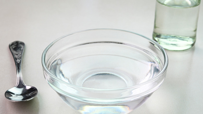 A bowl of vinegar with a glass of water behind it