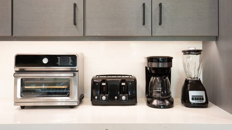 Miniature oven, toaster, coffee pot, and blender on kitchen countertop.