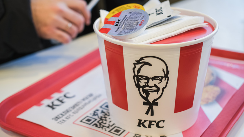 KFC bucket with a sauce container and napkins on top