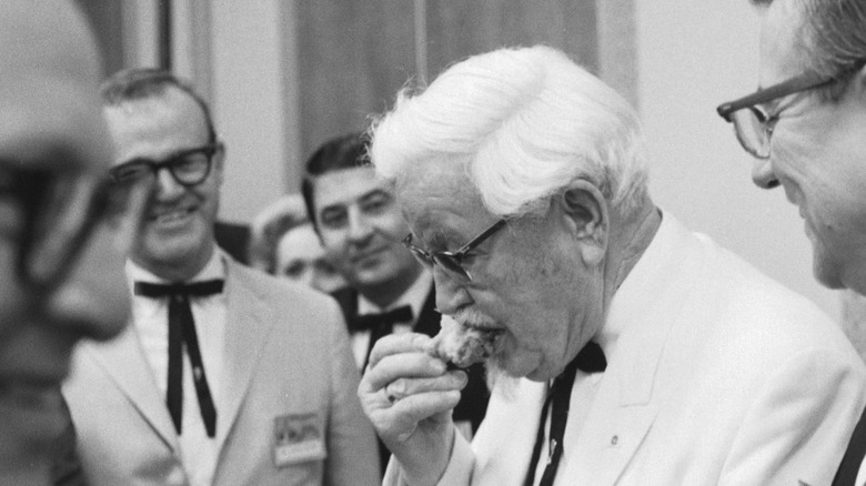 Colonel Harland Sanders eating a piece of fried chicken