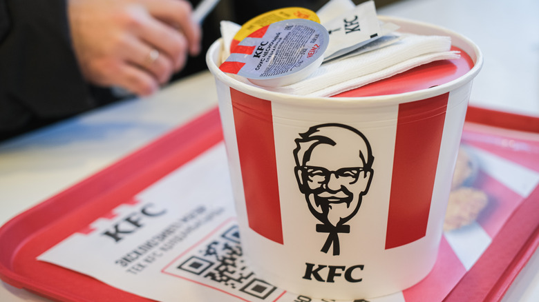 A KFC red and white-striped bucket on a tray