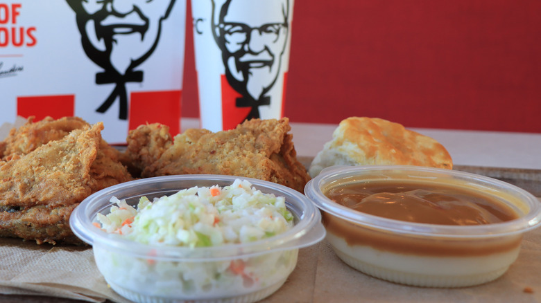 A KFC box meal with mashed potatoes and gravy, coleslaw, a biscuit, and two pieces of chicken