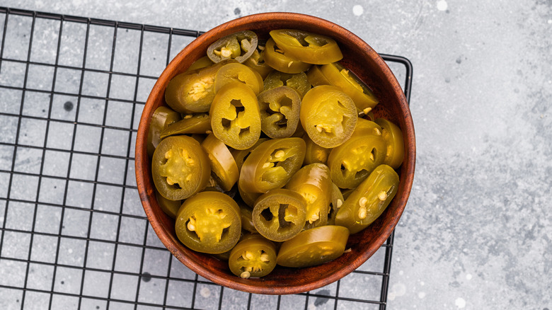 Chopped pickles jalapeños in a bowl over a wire rack