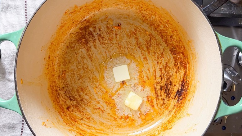 Butter melting in pot on stovetop with kimchi residue