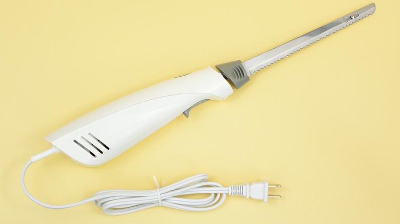 An electric carving knife on a yellow background