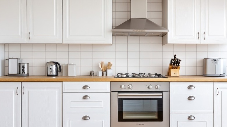 A modern kitchen countertop with an oven in the middle and various appliances sitting on top of it.