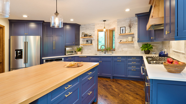 bright blue painted kitchen cabinets with white stone and butcher block counters.
