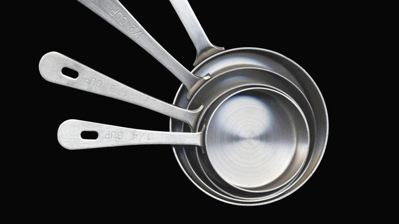 set of metal measuring cups on black background