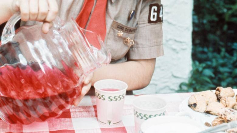 A girl scout pouring red Kool-Aid into a cup