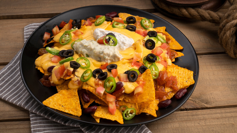 Nachos with spicy beef, cheese sauce scattered with scallions
