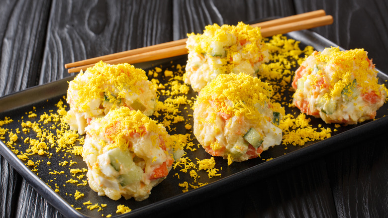 Five servings of Korean gamja potato salad on a black serving tray with chopsticks