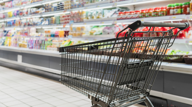 An empty shopping cart in a grocery aisle.