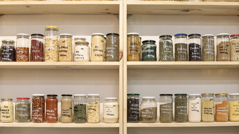 Wooden kitchen pantry shelves filled with jars of dry goods