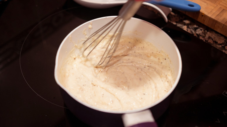 Whisking bechamel sauce on a pan. Motion blurred of homemade bechamel sauce for italian lasagna.