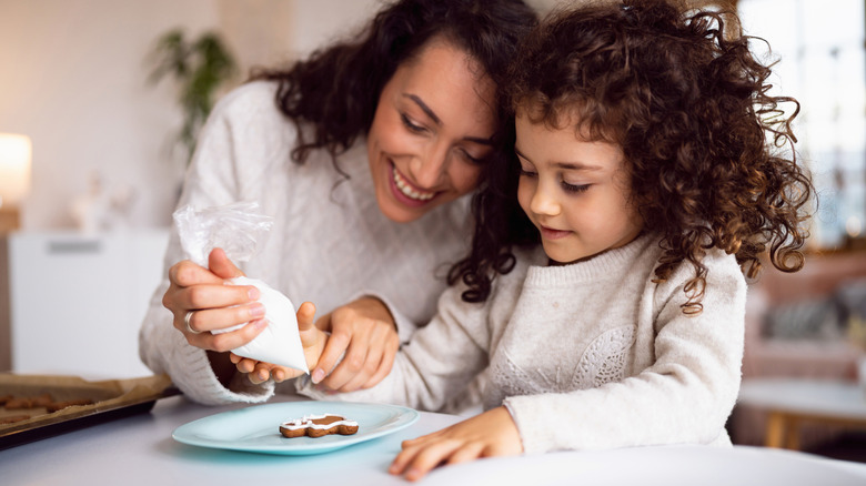 Mother decorating cookies with her daughter