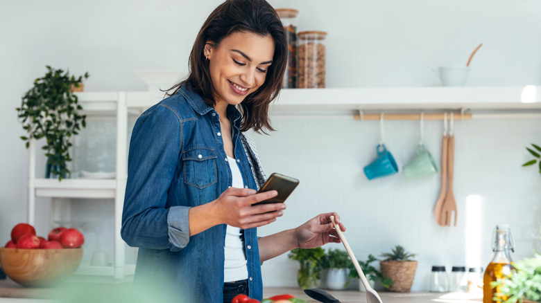 Woman looking at her phone while cooking