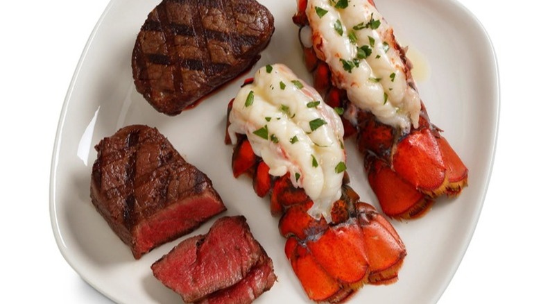 Two filet mignon steaks and two lobster tails on a white plate