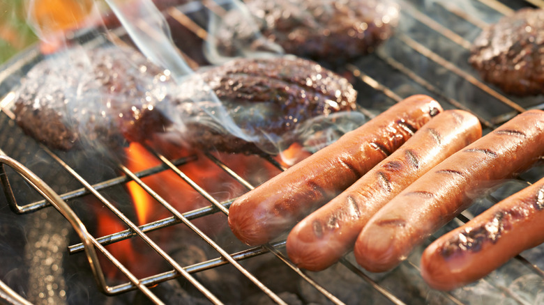 Burgers and hot dogs grilling on an outdoor grill.