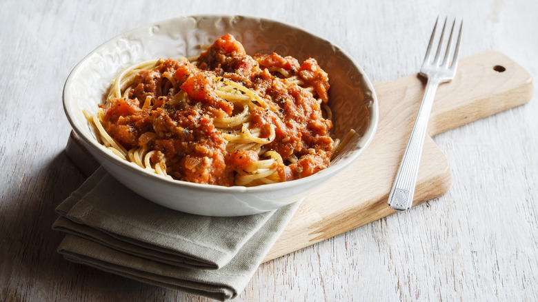 a bowl of spahetti bolognese with a fork on the side
