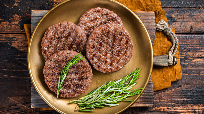 Cooked burger patties in a plate with fresh herbs