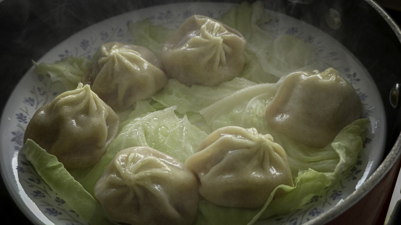 a close-up shot of dumplings in a steamer basket layered with cabbage leaves