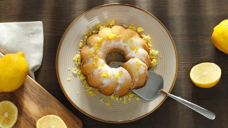 A round lemon cake with grated lemon zest on a plate