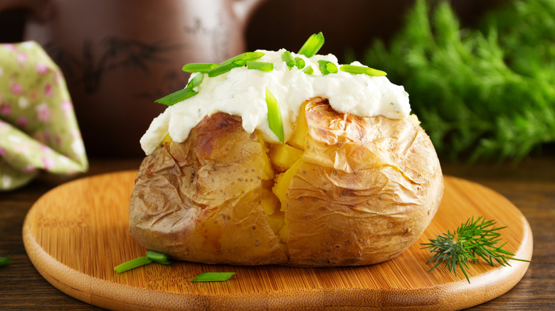 Baked potato on wooden board.