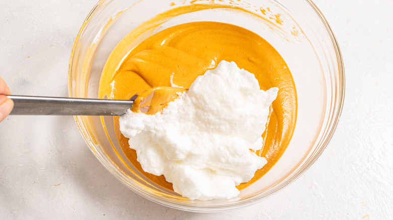 Bowl with carrot puree and egg whites being folded into it