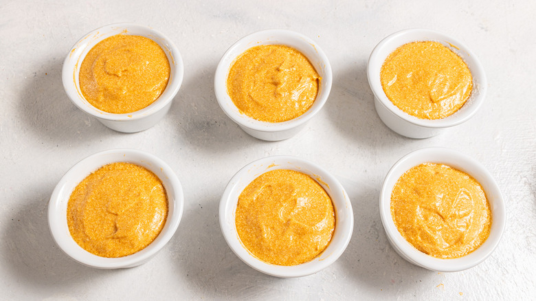 Six ramekins with carrot souffle ready to bake