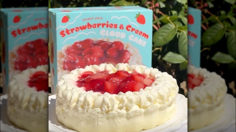 Trader Joe's Strawberries & Cream Cloud Cake on a cake stand in front of its packaging
