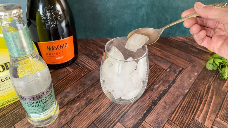 Filling balloon glass with ice using bar spoon