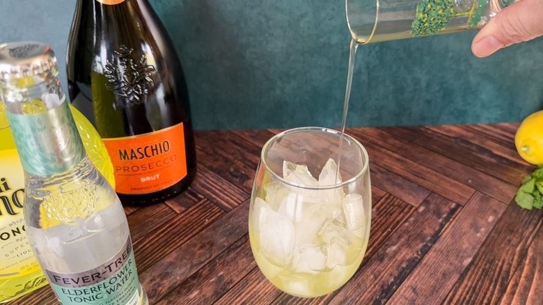 Pouring limoncello over ice in a balloon glass