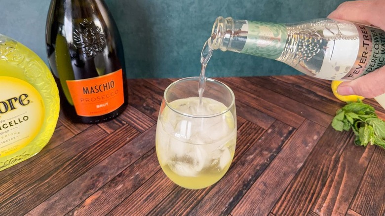 Pouring tonic water into an Amalfi spritz in a balloon glass