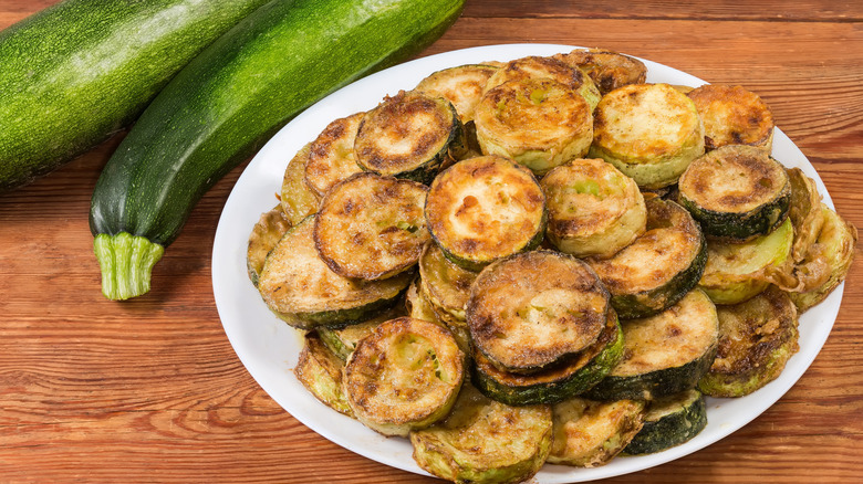 Baked fried zucchini beside whole zucchini on plate