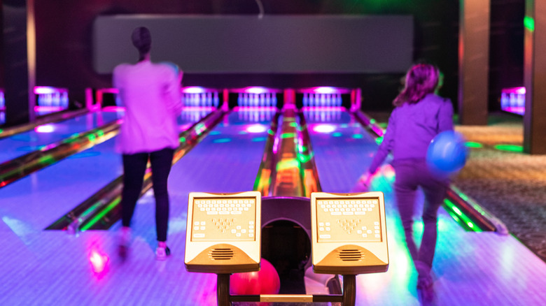 Two people bowling in purple lighting