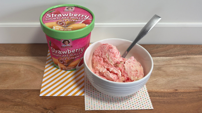 Little Debbie Strawberry Shortcake Rolls ice cream next to a bowl of ice cream on colored napkins and cutting board