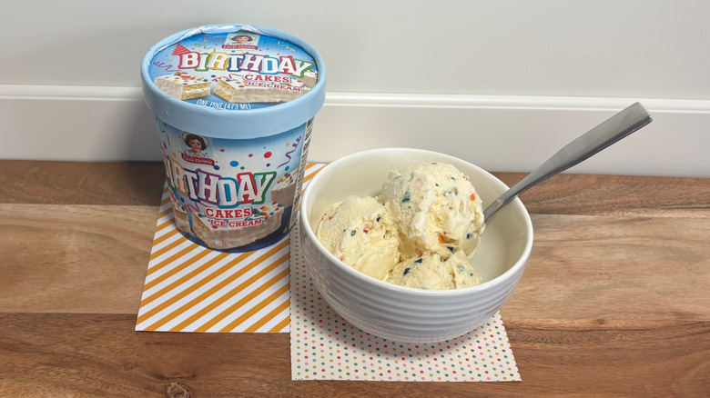 Little Debbie Birthday Cakes ice cream next to a bowl of ice cream on colored napkins and cutting board
