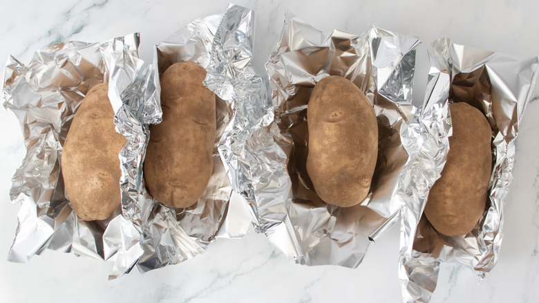 Four baking potatoes loosely wrapped in foil