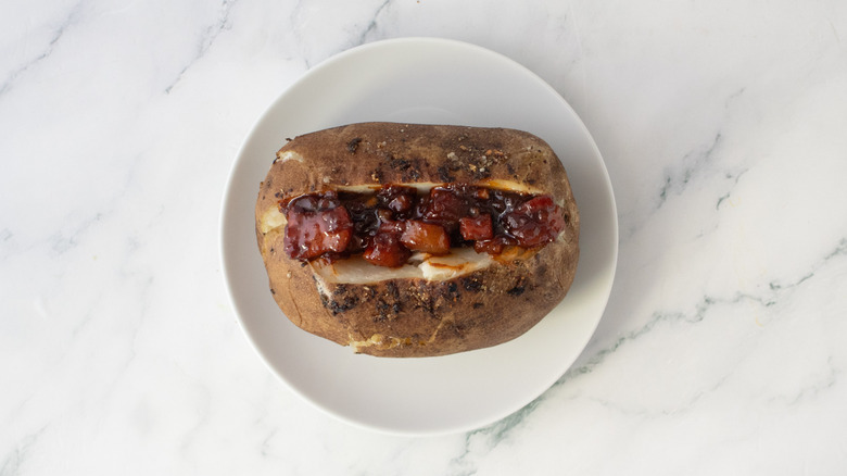 Baked potato topped with barbecue sauced pork belly