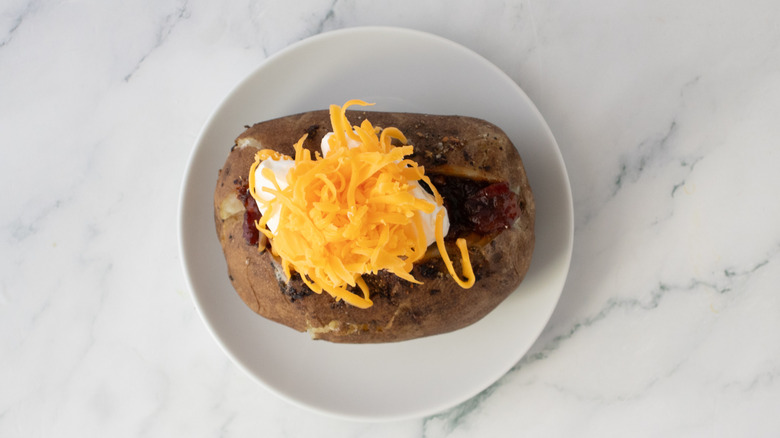 Baked potato topped with sour cream and cheddar cheese