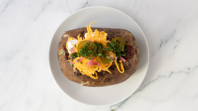 Fully loaded baked potato on a plate.