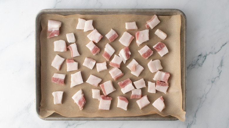 Raw pork belly on a parchment-lined baking sheet